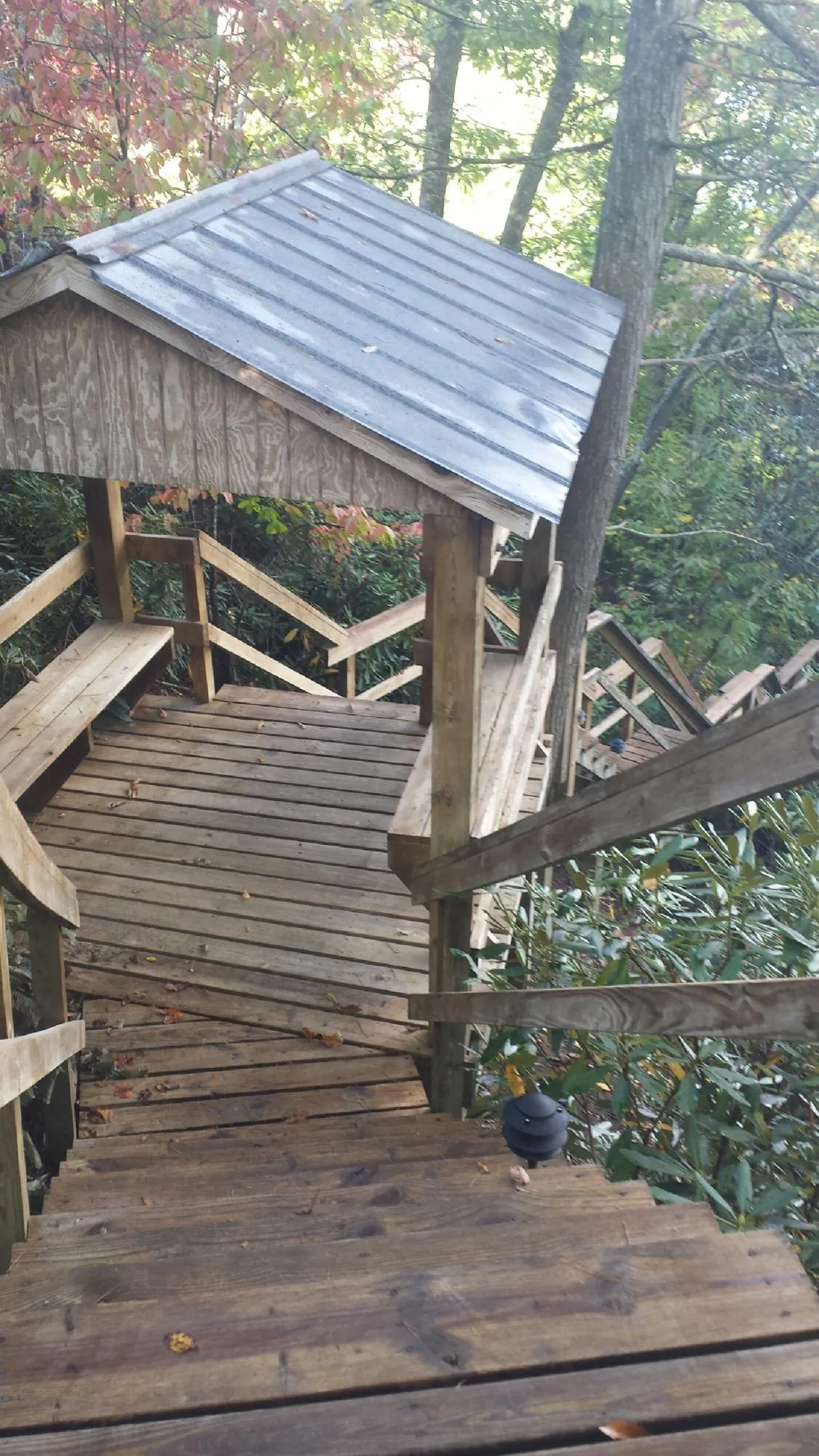 Metal roofed shelter over wooden steps on a wooded walkway — Skylight Repair & Installation work by our crew in Kingsville