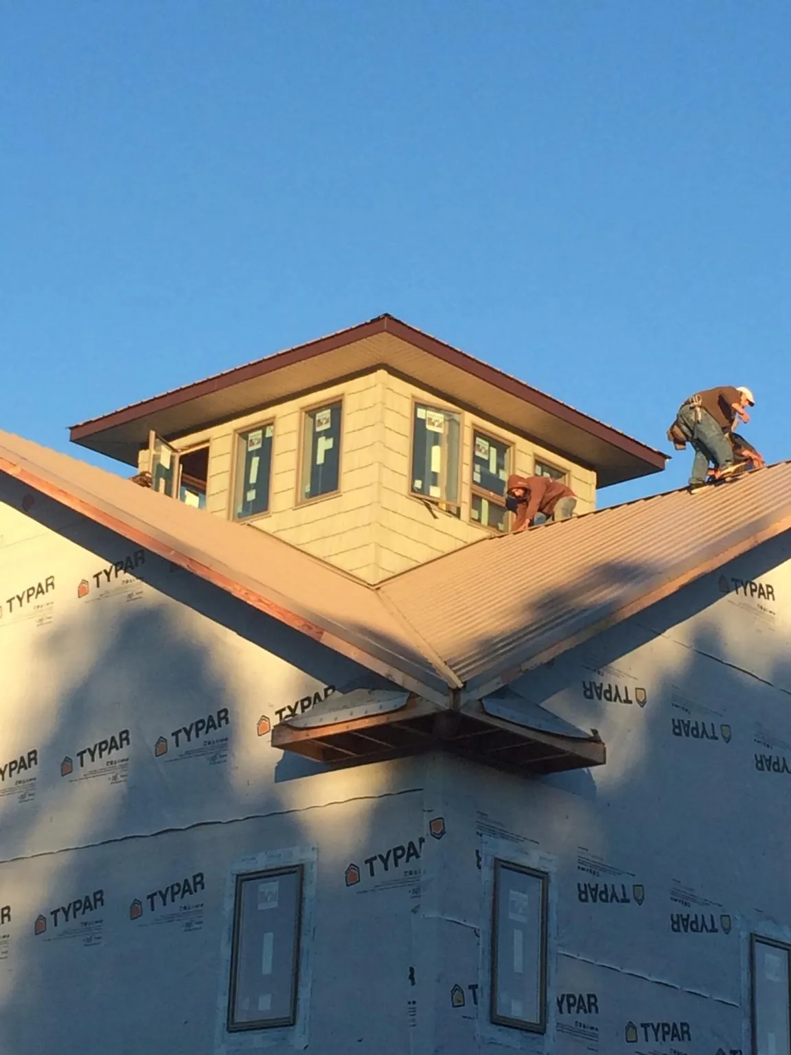 Roofers working around a rooftop cupola on a new metal roof at sunset — Roof Waterproofing in Kingsville by Roofing Brothers